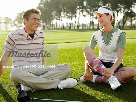 Two young golfers sitting on court, smiling