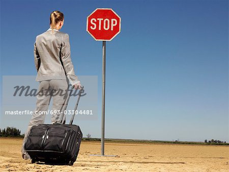 Businesswoman in Desert Looking at Stop Sign