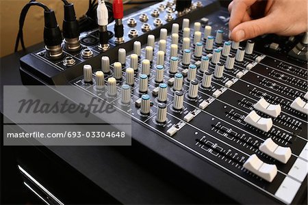 Man adjusting knob on mixing console, close-up.