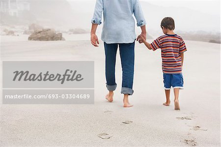 Vater und Sohn (5-6) Hände halten, Wandern am Strand, Rückansicht