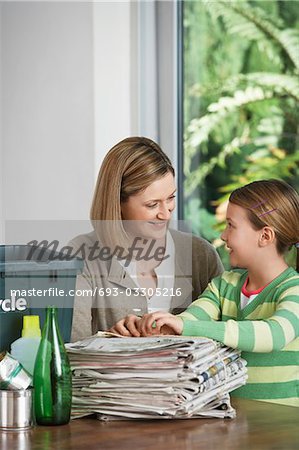 Woman and girl preparing waste paper for recycling, smiling