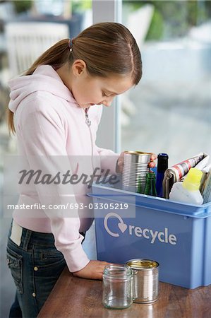 Girl (10-12) putting empty vessels into recycling container, side view