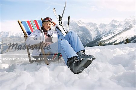 Skieuse assis sur une chaise longue dans les montagnes