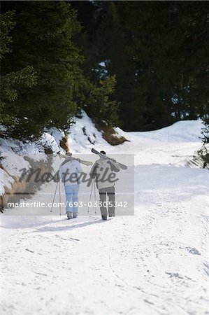 Couple ski en descendant la pente de ski, transportant des skis sur les épaules, vue, vue surélevé arrière
