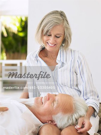 Man resting head on woman's lap, sitting on verandah