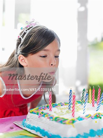 Young girl (7-9) blowing out birthday candles, close-up