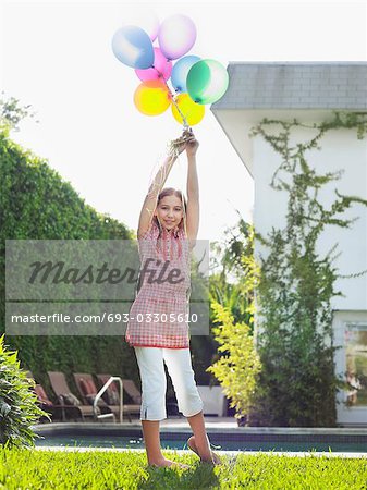 Portrait of girl (10-12) holding bunch of balloons over head