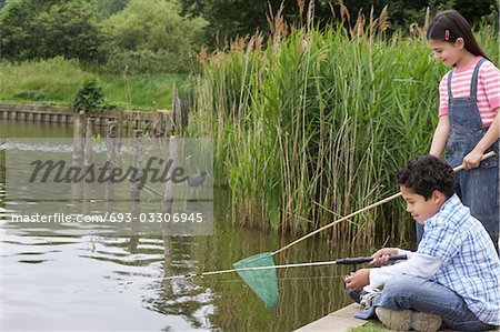 Brother and sister (5-9) fishing in river