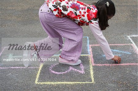 Girl (7-9) playing hop-scotch in school playground