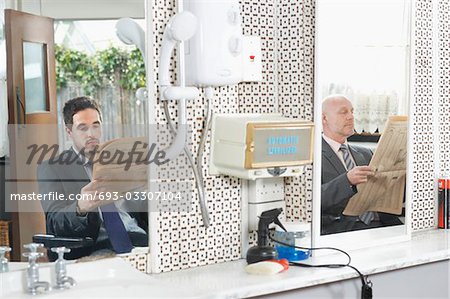 Zwei Geschäftsleute warten Haarschnitt in Friseur