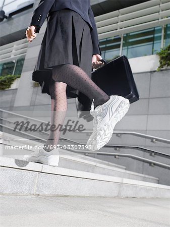 Business woman wearing running shoes, walking up steps, low section, low angle view