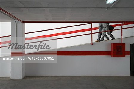 Two businessmen walking down ramp in parking garage