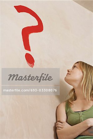 Woman leaning against wall with painted question mark