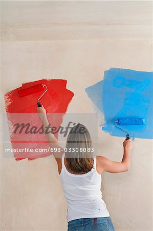 Mur peinture femme avec rouleaux à peinture, vue arrière