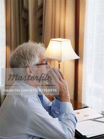 Geschäftliche Mann mit Händen gefaltet sitzend am Schreibtisch, erhöhte Ansicht, Seitenansicht