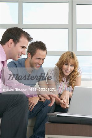 Real estate agent using laptop with couple in new home