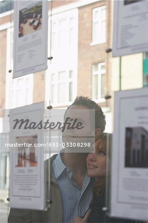 Couple regardant par la fenêtre aux agents immobiliers