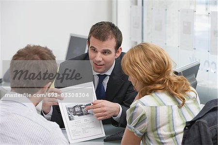 Brochure d'observation avec l'agent immobilier au bureau de couple