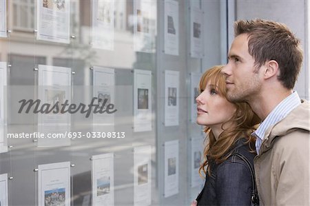 Couple à la recherche dans la fenêtre à l'extérieur des agents immobiliers