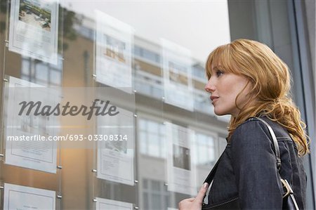 Femme à la recherche dans la fenêtre à l'extérieur des agents immobiliers