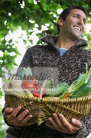 Man holding fruit and vegetable basket, outdoors