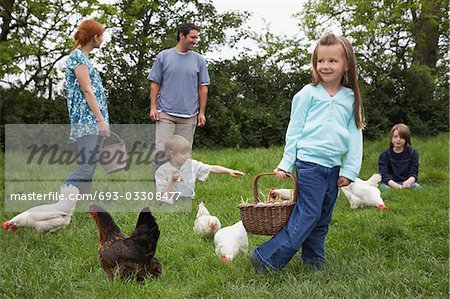 Parents and three children (5-9) with hens in garden