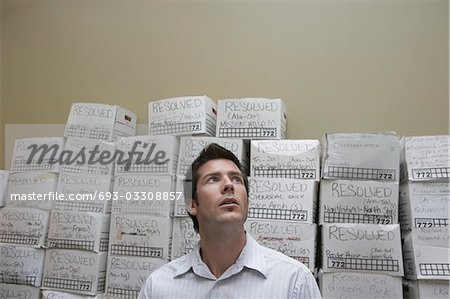 Geschäftsmann vor Stack Anmeldetag Stand-Boxen im Lagerraum, Flachwinkelansicht