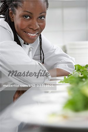 Chef féminin avec des assiettes de salade dans la cuisine, portrait