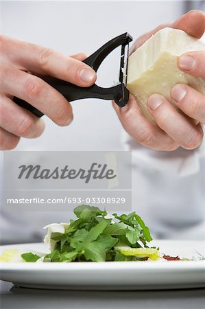 Chef masculin, râper le fromage sur la salade, moyenne section