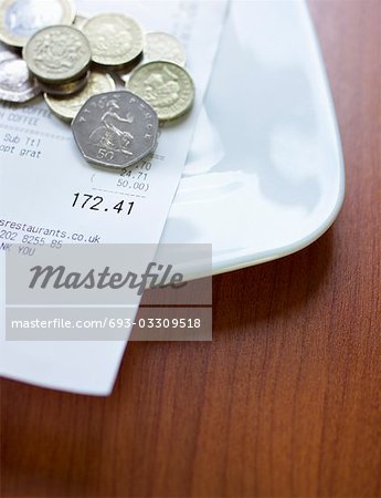 Pound coins and bill on plate, close-up