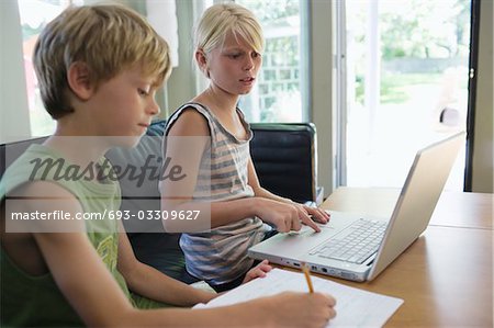 Geschwister (6-8) sitzen am Tisch, die Hausaufgaben mit laptop