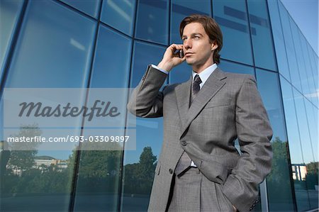 Homme d'affaires à l'aide de téléphone portable à l'extérieur de l'immeuble de bureaux