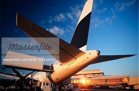 Tail fin of airplane at airport, sunset