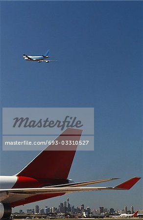 Close-up of airplane's tail fin, flying plane in background