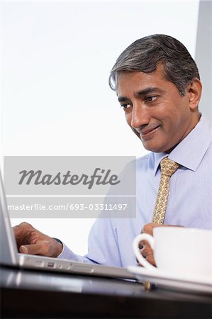 Business man using laptop, smiling, low angle view