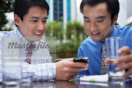 Homme d'affaires deux à l'aide de téléphone portable assis dans le café en plein air