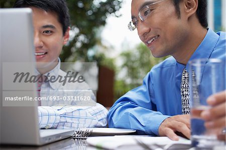 Homme d'affaires deux utilisant un ordinateur portable assis dans le café en plein air, gros plan
