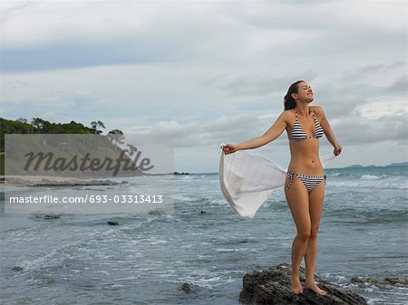 Young Woman Standing on Rock at Beach