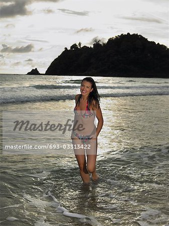 Young Woman Wading in Ocean at Sunset