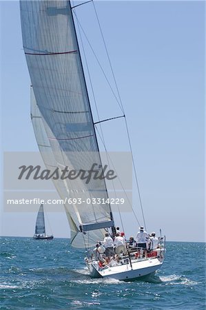 Crew on board yacht in competitive team sailing event, California