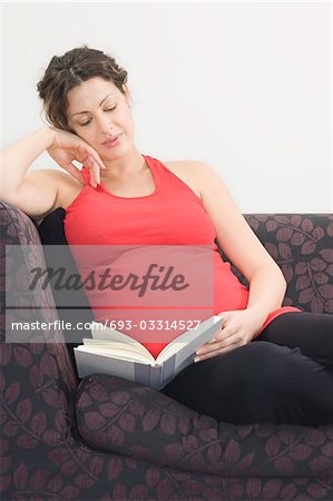 Enceinte femme lisant sur canapé