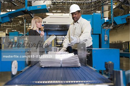 Mann arbeitet auf Zeitung-Produktionslinie in Zeitung-Fabrik