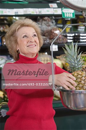 Haute femme pesant ananas en supermarché