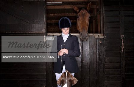 Horse rider with dog and horse at stable