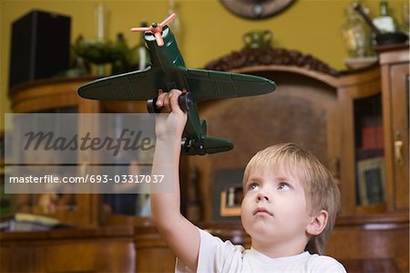 Jungen spielen mit Modellflugzeug im Haus