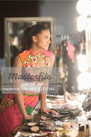 Woman leans on dressing table of cosmetics