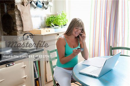 Femme enceinte, assis à la table de cuisine avec ordinateur portable