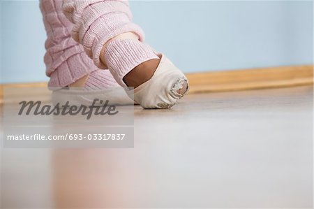 Young woman positions feet in ballet rehearsal