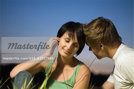 Couple assis à écouter de la musique sur des écouteurs partagés
