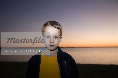 Boy stares at camera from sunset beach